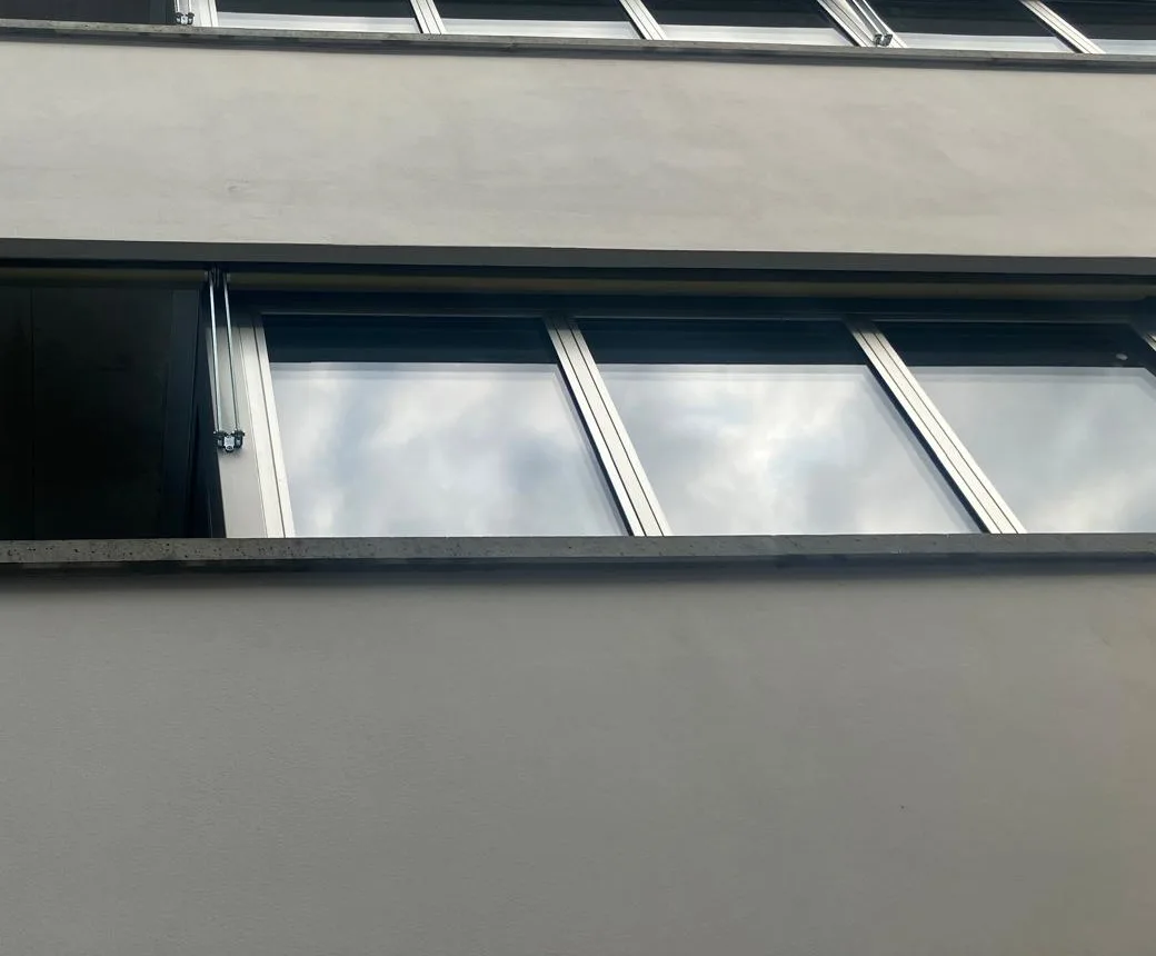 Ebener, grau gestrichener Putz an Brüstung und Fensterband