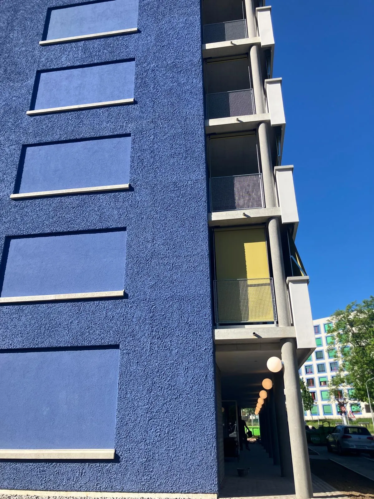Wohnhaus mit kräftig blau gestrichener Putzfassade und gelben Loggien