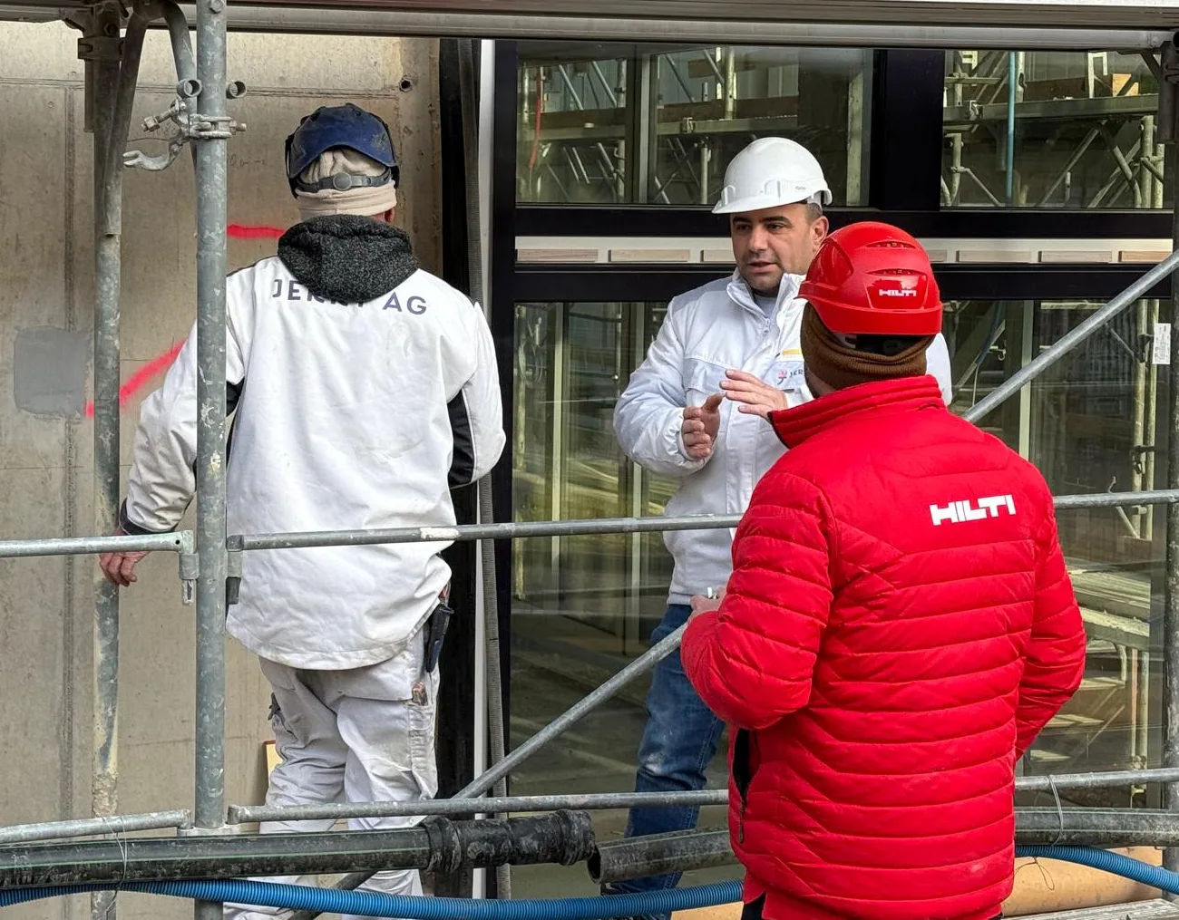 Team der Jerry AG auf der Baustelle: Besprechung am Gerüst